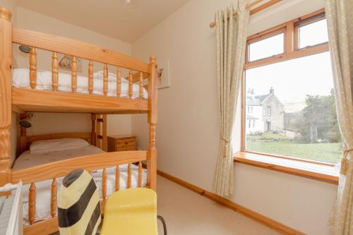 ein Schlafzimmer mit einem Etagenbett und einem Fenster in der Unterkunft Foxglove Cottage in Maybole