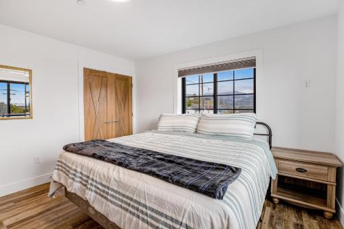 a white bedroom with a bed and two windows at Chinook Suite in Garibaldi