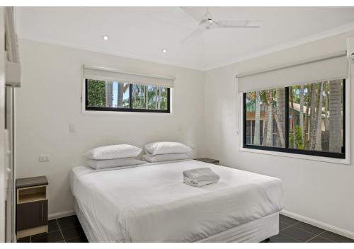 a white bedroom with a bed and two windows at Discovery Parks - Rockhampton in Rockhampton