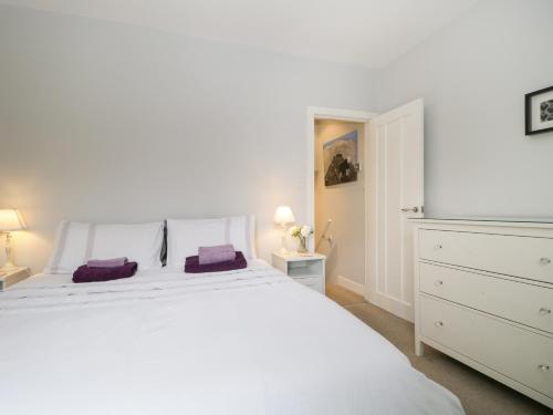 a white bedroom with a large white bed and a dresser at Banks Place in Keswick