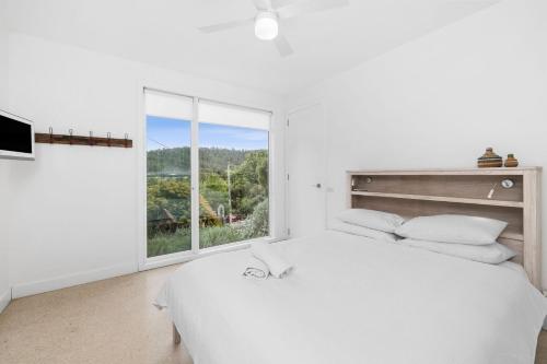 a bedroom with a white bed and a large window at Drift - Luxury, location and ocean views in Wye River