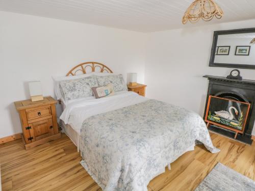 a bedroom with a bed and a fire place at Mary Kate's Cottage in Narin