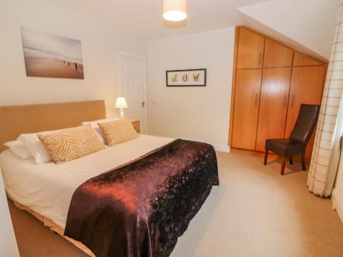 a bedroom with a large bed and a chair at No 4 Lansdowne Village in Kenmare
