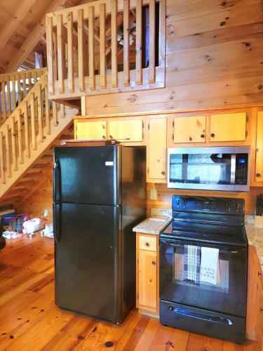 a kitchen with a black refrigerator and a staircase at LUXURY CABIN WITH WATERVIEW AND PRIVACY, hiking in Blue Ridge