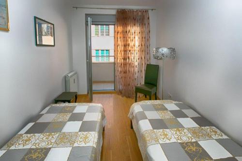 Habitación con 2 camas y una silla verde. en Apartment 32, en Belgrado