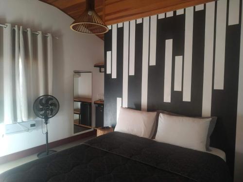 a bedroom with a black and white striped wall at Pousada Sítio Vale das Olivas in Aiuruoca