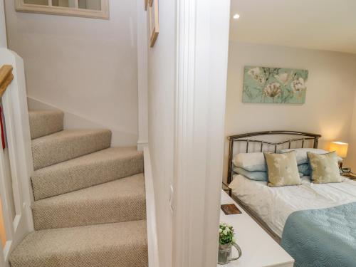 a small bedroom with a bed and a staircase at Church View in Bourton on the Water