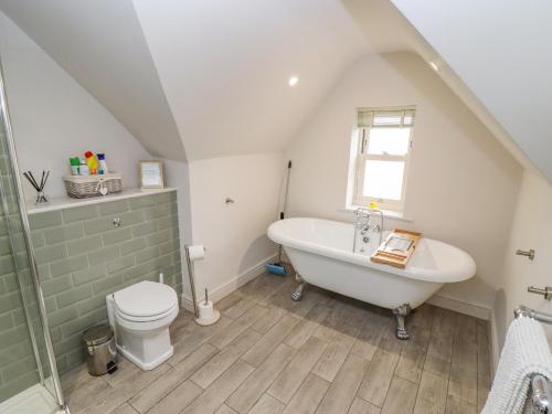 a bathroom with a white tub and a toilet at Church View in Bourton on the Water
