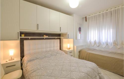 a bedroom with a bed with white cabinets and a window at Cozy Apartment In Rosolina Mare in Rosolina Mare