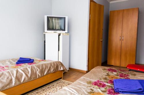 a bedroom with two beds and a tv on the wall at Hotel Tahar in Almaty
