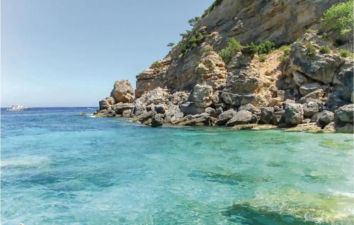 a rocky shore with a boat in the water at Rustico Gli Oleandri in Orgosolo