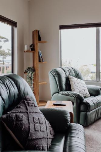 a living room with two couches and a table at Bicheno Gardens in Bicheno