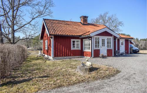 a red house with a dog sitting in front of it at Cozy Home In Söderköping With Kitchen in Söderköping