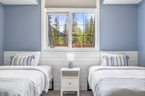 two beds in a room with a window at Mystic Chalet hosted by Fenwick Vacation Rentals in Canmore