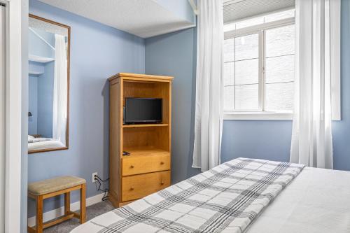 a blue bedroom with a bed and a television at Mystic Chalet managed by Little Sister Getaways in Canmore