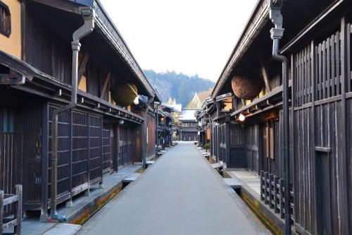 eine leere Gasse zwischen zwei Gebäuden mit Zäunen in der Unterkunft 桜丸 Sakuramaru in Takayama