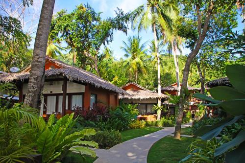 una casa en medio de un jardín con palmeras en Last Frontier Beach Resort-Adults Only en El Nido