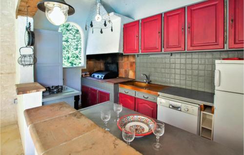a kitchen with red cabinets and a table with wine glasses at Cozy Home In Condorcet in Condorcet