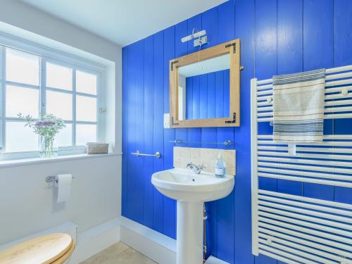 a blue bathroom with a sink and a mirror at Gables Cottage in Market Rasen