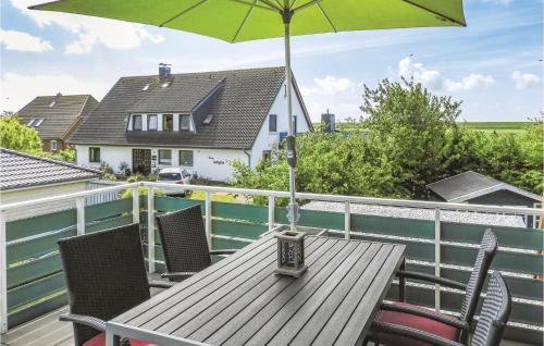 a wooden table with an umbrella on a balcony at 2 Bedroom Cozy Apartment In Dagebüll in Dagebüll