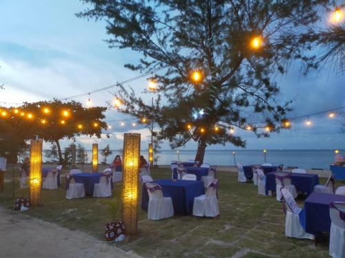 a group of tables and chairs with lights at Madu Tiga Beach and Resort in Tanjung Pinang 