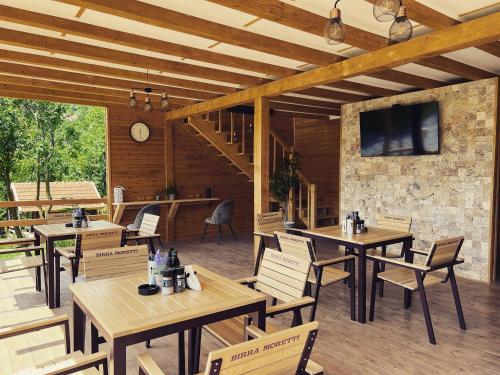 Bozioru的住宿－Tinutul Luanei Glamping Resort，餐厅设有木桌、椅子和电视。
