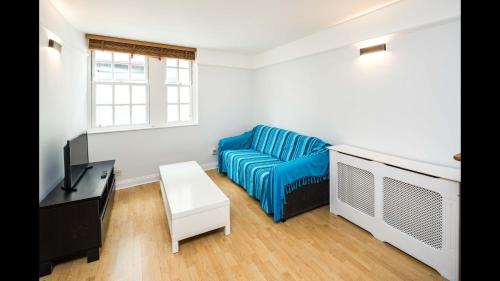 a living room with a blue couch and a tv at Delightful 1-bedroom Apartment In Whitechapel in London