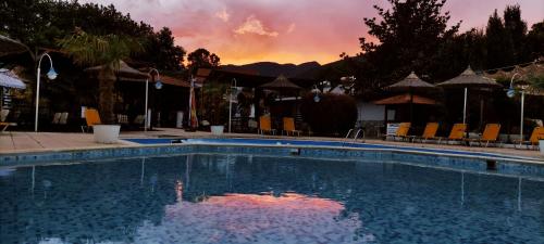 a swimming pool with a sunset in the background at Oasi in Kato Loutraki