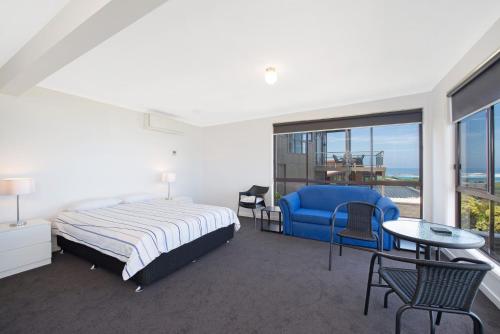 1 dormitorio con cama, silla azul y ventana en Cape Marengo, en Marengo