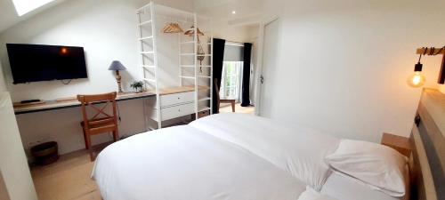 a bedroom with a bed and a desk with a television at La Ferme du Soyeuru in Spa