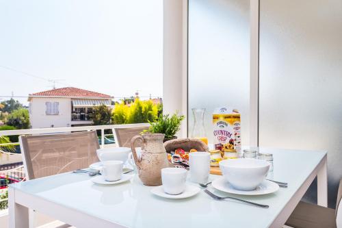 a white table with bowls and cups on a balcony at Villa Velvet in Villeneuve-Loubet