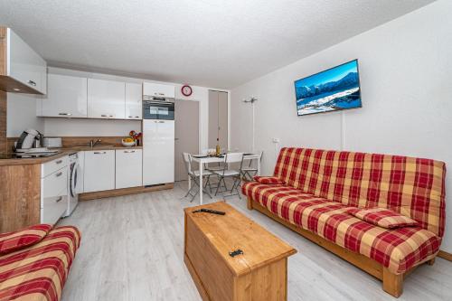 ein Wohnzimmer mit einem Sofa und einem Tisch sowie eine Küche in der Unterkunft appartement au pied des pistes in Orcières
