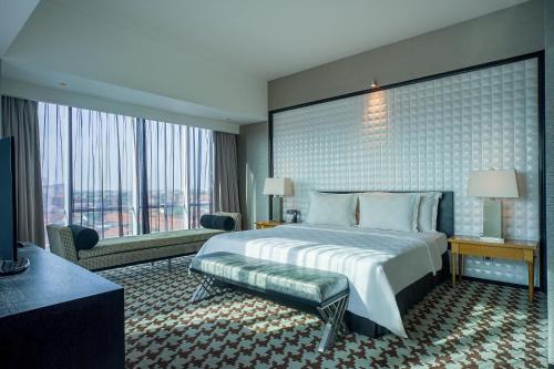 a hotel room with a bed and a large window at ARTOTEL TS Suites Surabaya in Wonokromo