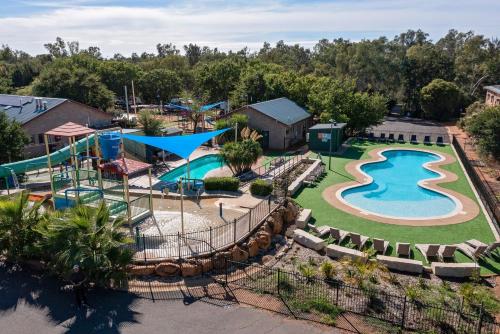 a patio area with a pool and lawn chairs at Discovery Parks - Dubbo in Dubbo
