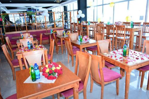 bruhway hotel في أديس أبابا: مطعم بطاولات وكراسي خشبية عليها ورد