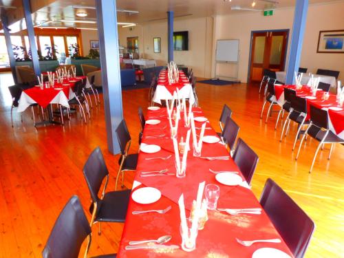a long dining room with red tables and chairs at Townhouse Motel Cowra in Cowra