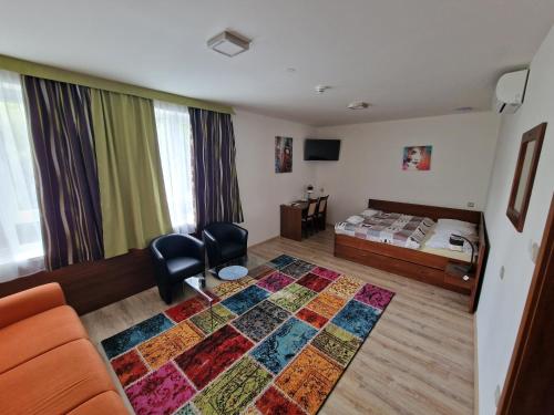 um quarto com uma cama, um sofá e um tapete em Penzion PKO Nitra em Nitra