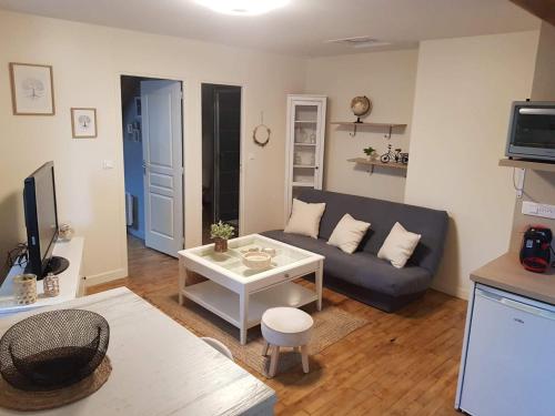 a living room with a couch and a table at Logement à Brive, près du centre-ville et de la gare - Climatisation, fibre internet et stationnement gratuit in Brive-la-Gaillarde
