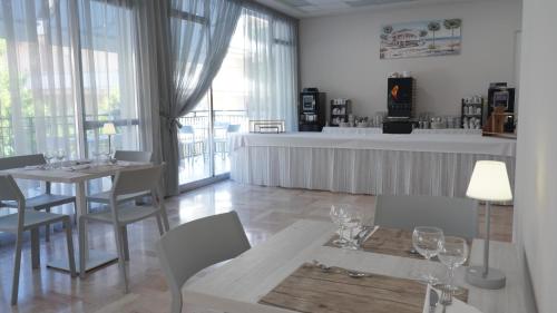 een eetkamer met een tafel, stoelen en ramen bij Lively Hotel in Bellaria-Igea Marina