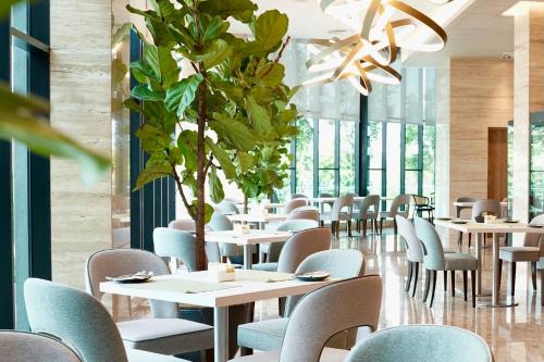 a dining room with tables and chairs and a plant at Opero Hotel Southkey Johor Bahru in Johor Bahru
