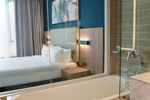 a bathroom with a tub and a bed and a shower at Opero Hotel Southkey Johor Bahru in Johor Bahru