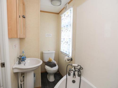 a bathroom with a sink and a toilet and a tub at Trewan Lodge in Holyhead