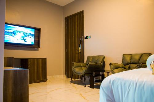 a room with two chairs and a tv on the wall at Hotel Horizon Entebbe in Entebbe
