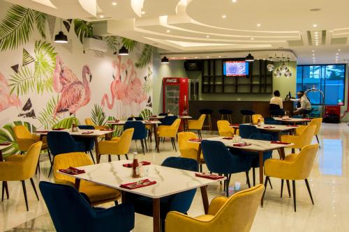 a restaurant with tables and chairs and a wall with flamingos at Hotel Horizon Entebbe in Entebbe