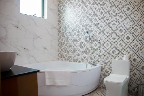 a bathroom with a white tub and a toilet at Hotel Horizon Entebbe in Entebbe