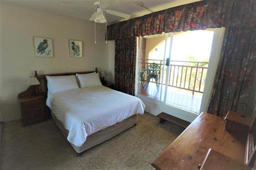 a bedroom with a bed and a window with a balcony at Mallorca 13 Duplex in Umdloti