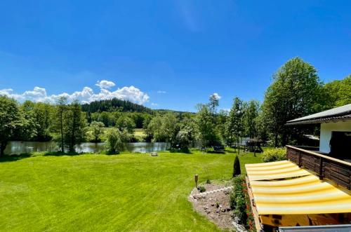 a large yard with a lake and a house at Gasthof Pension Fischerstüberl in Blaibach