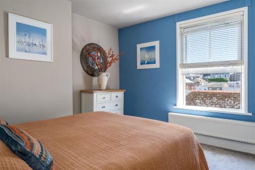 een blauwe slaapkamer met een bed en een raam bij Gulls Rest - Charming Cottage in the heart of historic Dartmouth in Dartmouth