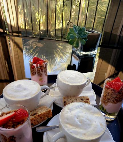 a table topped with cups and plates of food at Waterfalls Boutique Hotel in Pretoria