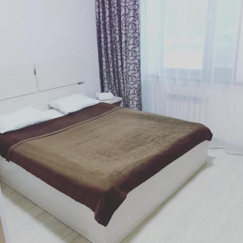 ein Schlafzimmer mit einem großen Bett mit einer braunen Decke in der Unterkunft Гостиница"Hostel" in Qaraghandy